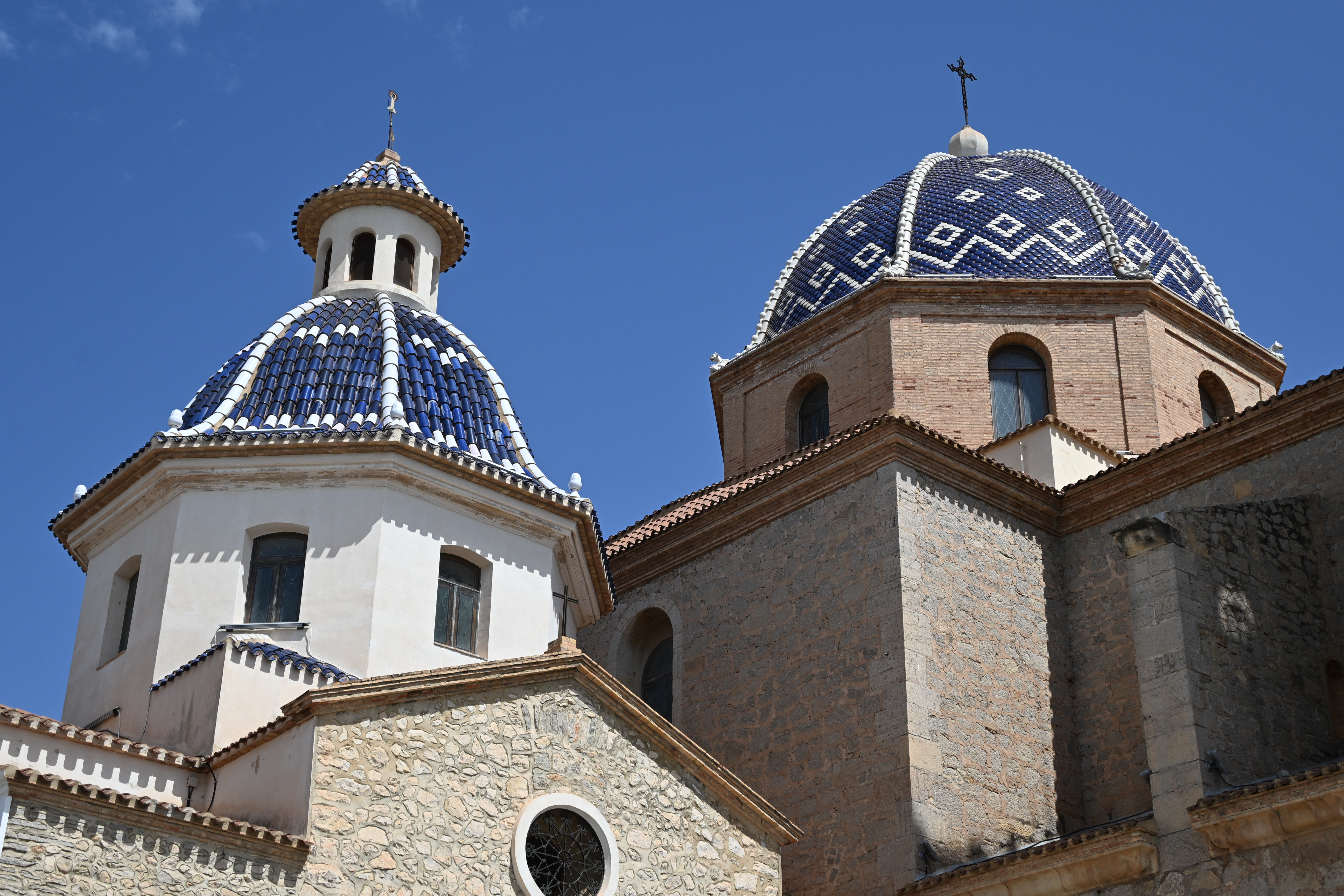 Zwei blau-weiß gekachelte Kuppeln der Kirche Nuestra Señora del Consuelo in Altea vor klarem blauem Himmel